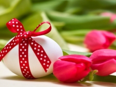 Wit paasei met rode strik en rode tulpen